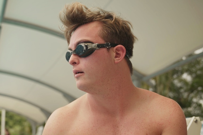 Bobby Pate sits beside the pool in swimming goggles.