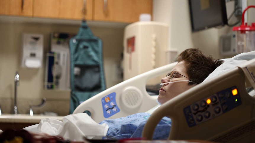 A woman lies in a hospital bed