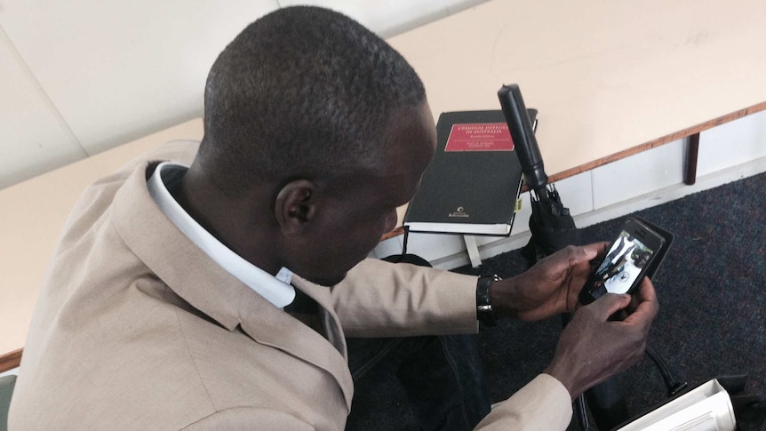 Deng Adut looking at photos of loved ones