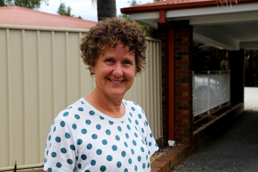 A smiling woman stands in the driveway of a motel.