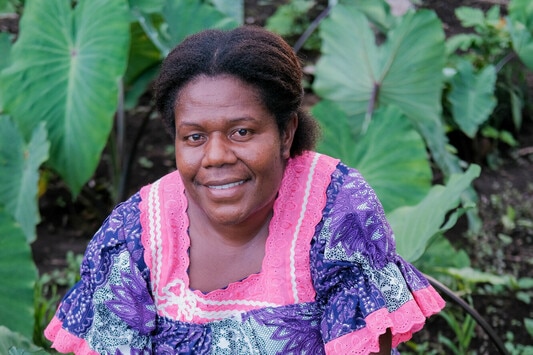 A woman sitting near crops smiles