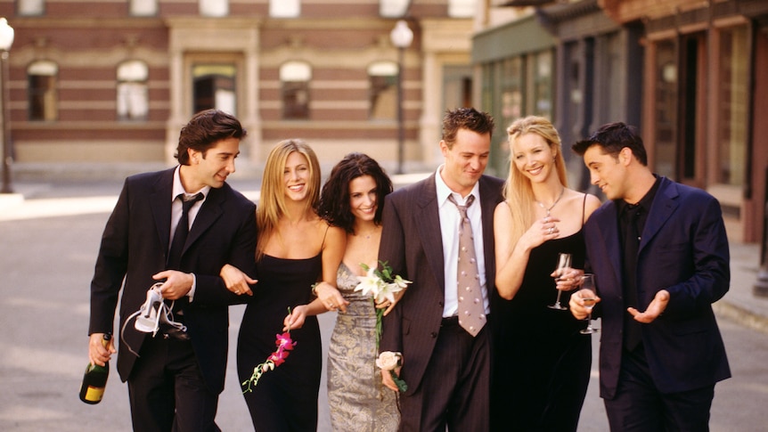 Five people stand in a New York street, they are happy and joking together