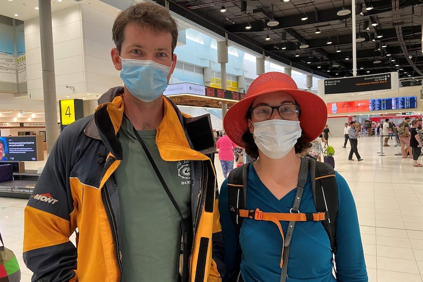 A man and woman wearing face masks at the airport
