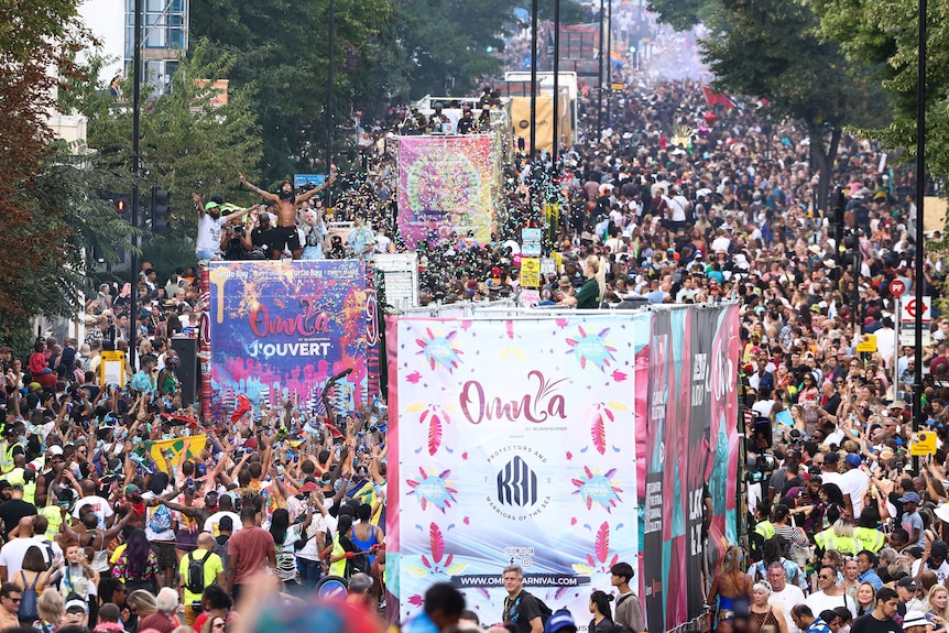 Thousands of people crowd down a street for the Notting Hill Carnival. 