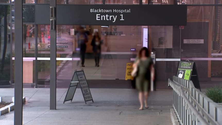 A view of the front glass sliding doors of Blacktown Hospital, people walking through