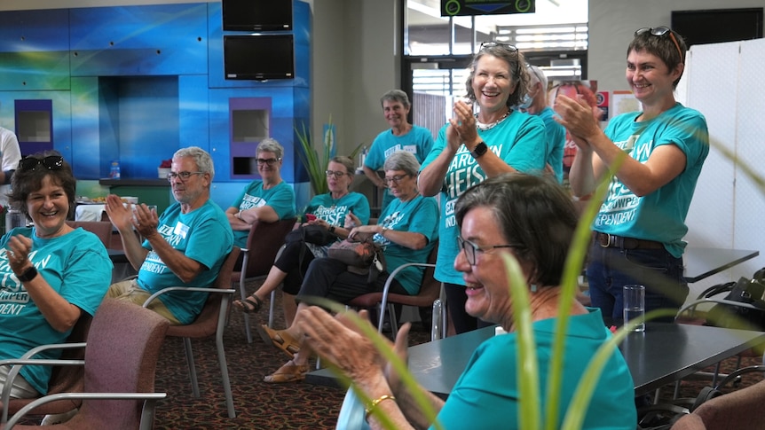 Five women in Caz4Cowper teal shirts clapping in support