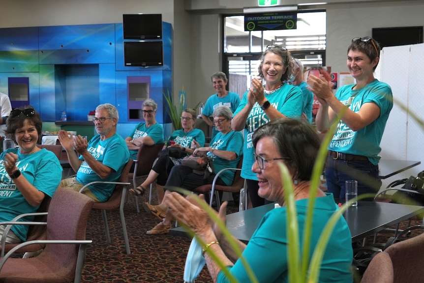 Five women in Caz4Cowper teal shirts clapping in support