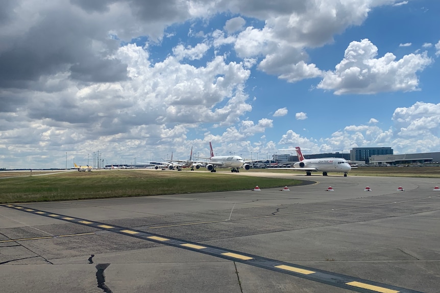 Planes wait in line to take off from Melbourne Airport on a partly cloudy day.