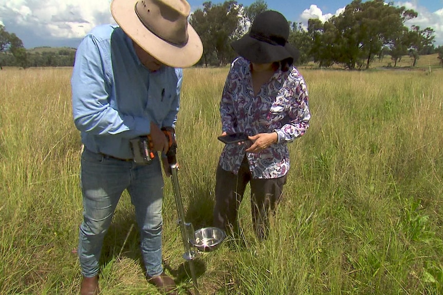 Photo of a man and a woman on a farm measuring soil.