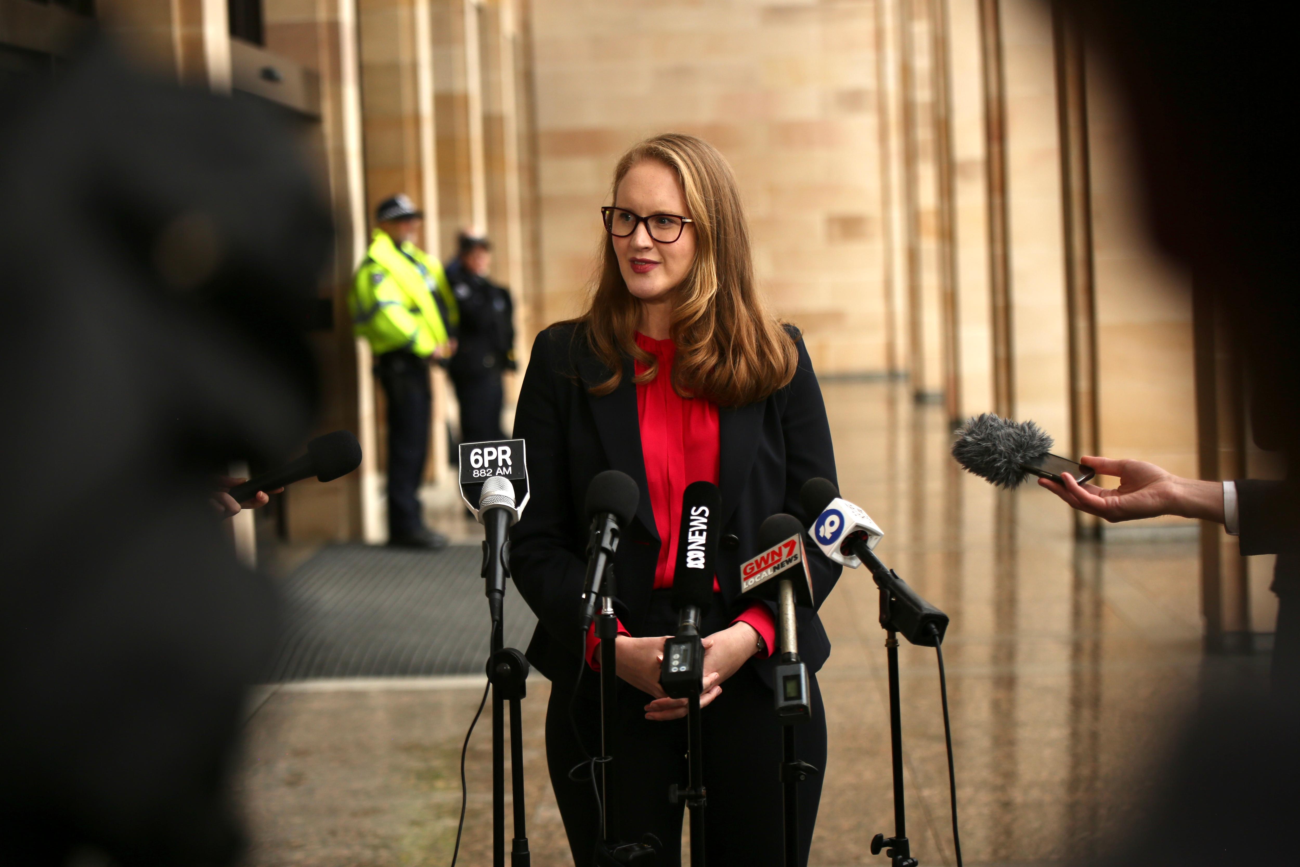 Un disparo amplio de Cassandra Winzar frente a un banco de micrófonos