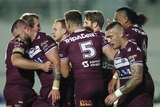 NRL players walk back to halfway after a try, quietly celebrating and patting each other on back.
