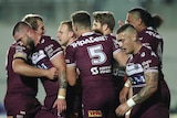NRL players walk back to halfway after a try, quietly celebrating and patting each other on back.