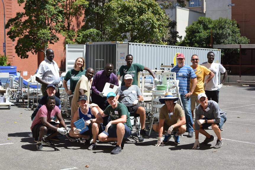 Volunteers gather for a photo with the medical equipment they have been loading into a shipping container