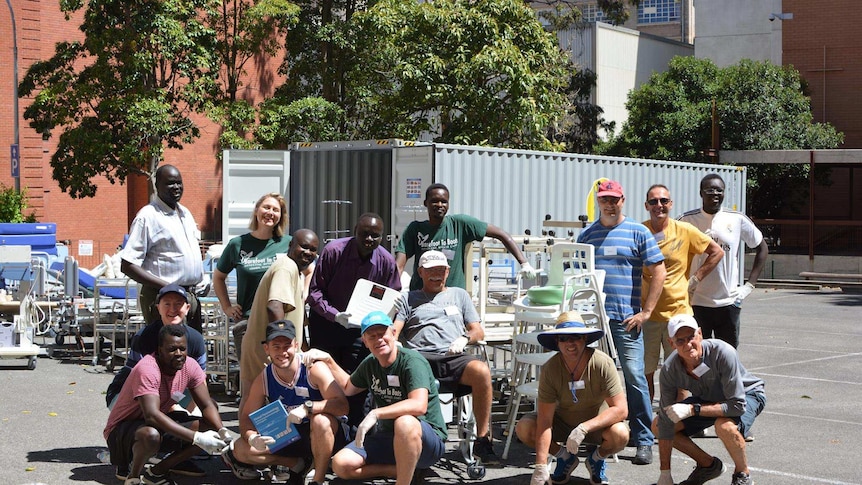 Volunteers gather for a photo with the medical equipment they have been loading into a shipping container