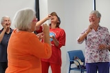 Four women pretending to drink tea and laughing