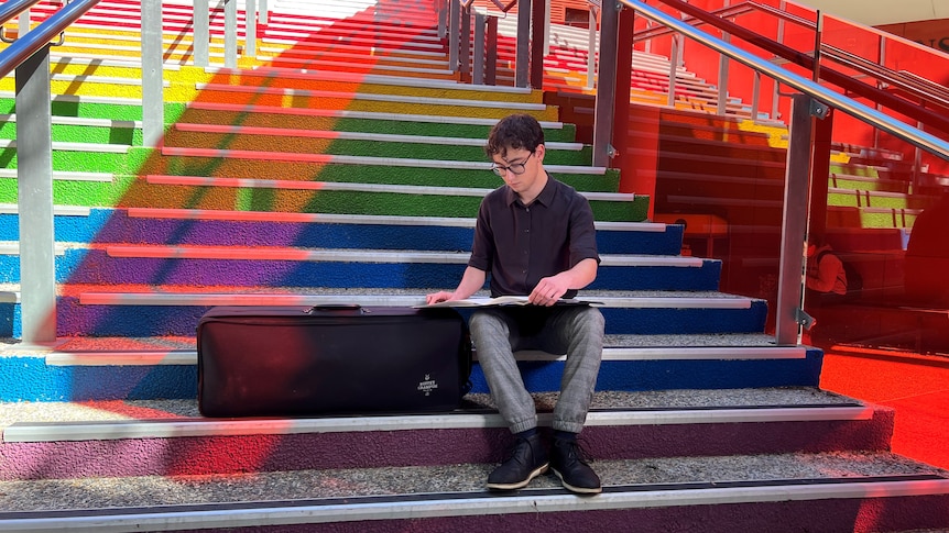 Hugo sits on rainbow stairs.