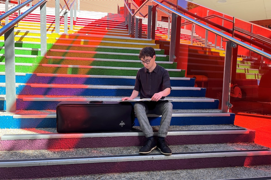 Hugo sits on rainbow stairs.