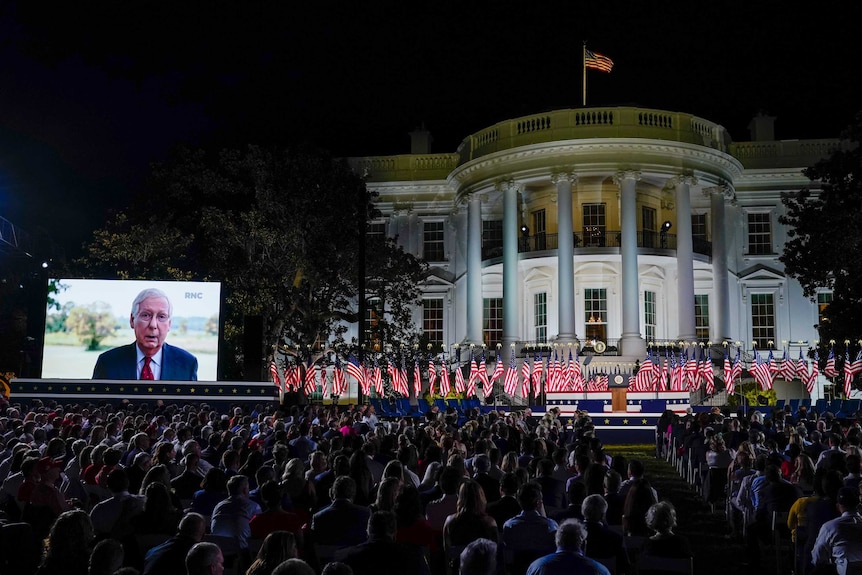 People watch video screens before President Donald Trump speaks from the South Lawn of the White House