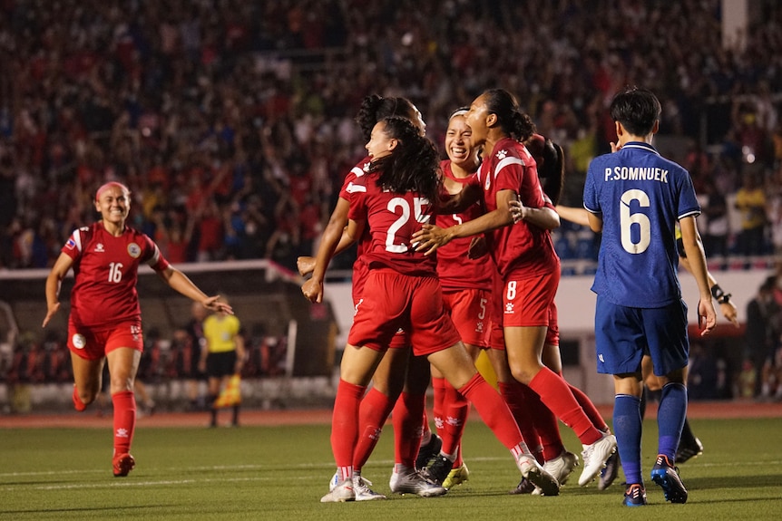 Philippines women's footballers celebrate with each other on the pitch