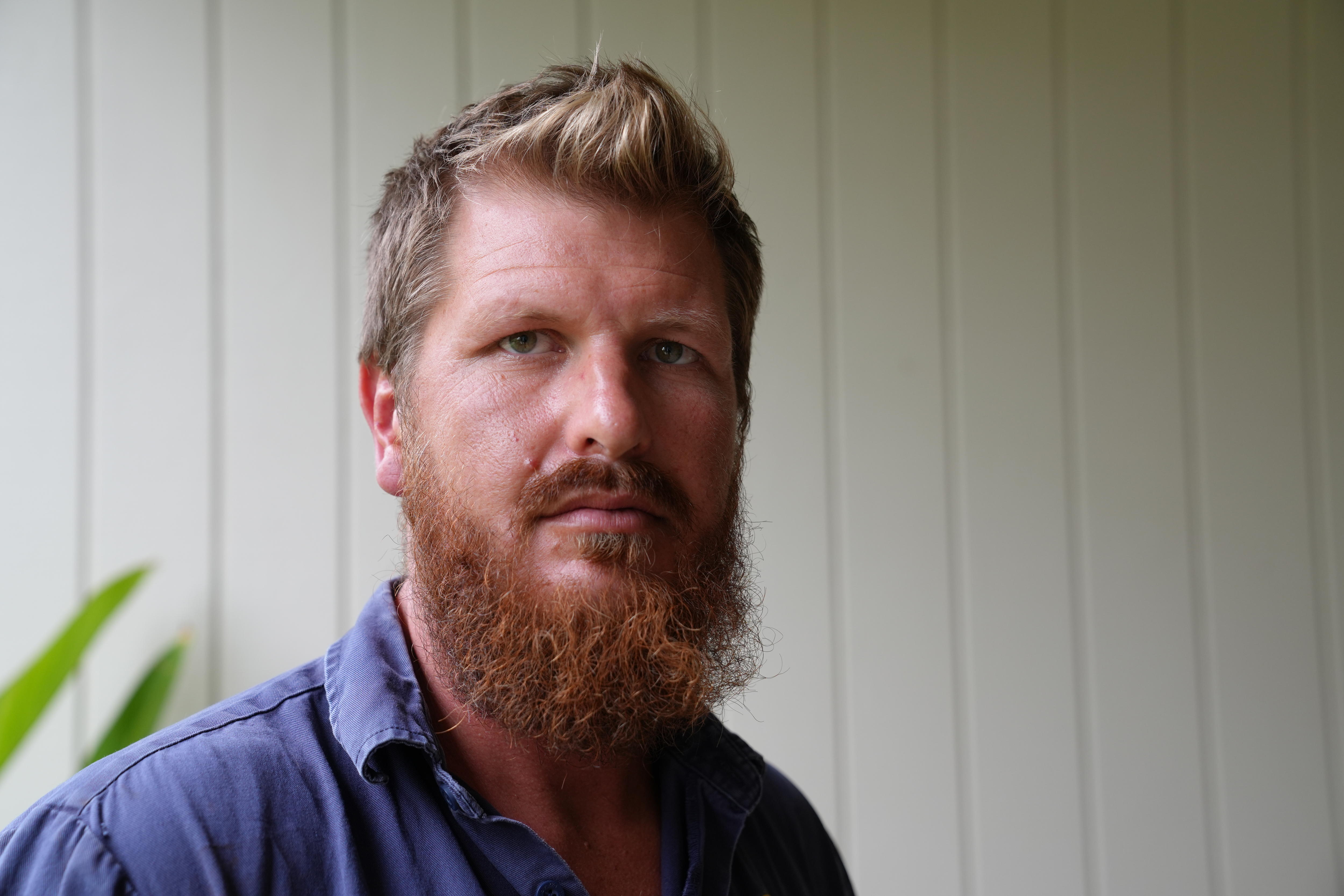 Un hombre con barba mira solemnemente a la cámara.
