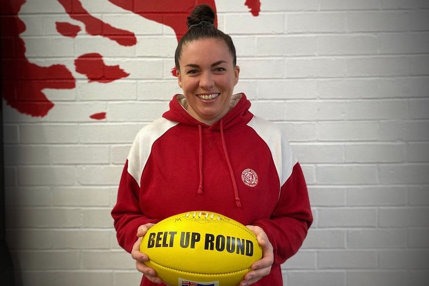 A woman in a red jumper holding a yellow football