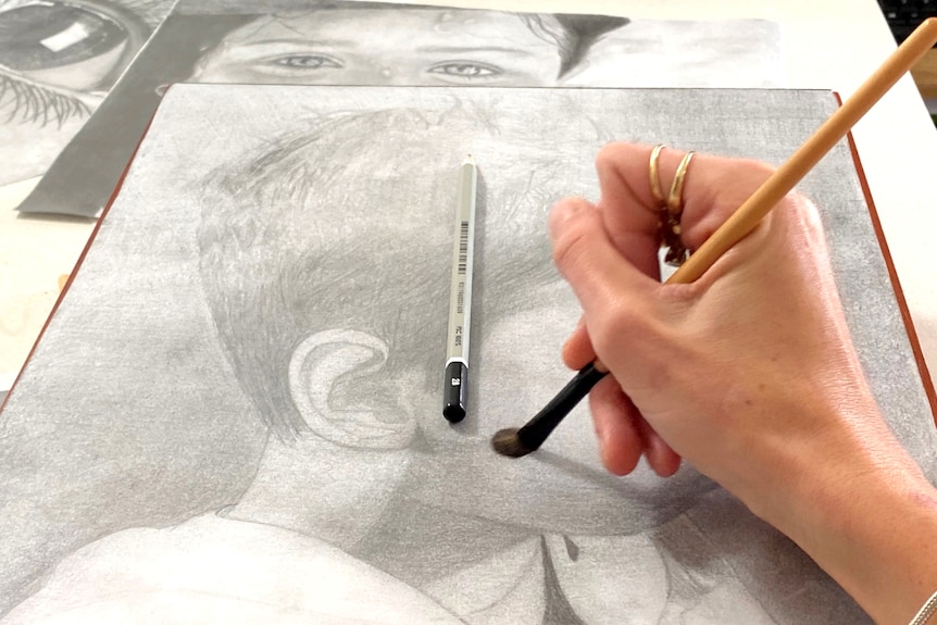 The hand of a woman sketching with pencils.