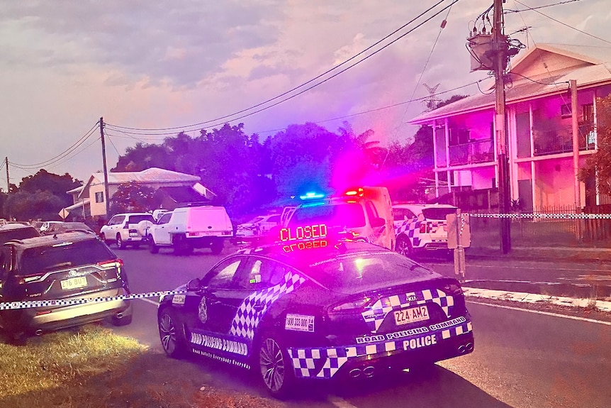 A police car, with a flashing closed sign on the roof, at a cordoned off street in Mackay.