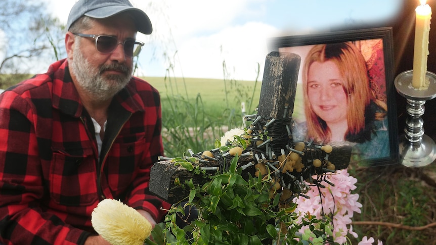 A man crouches by his sister's roadside grave with a picture of her young self and a candle.