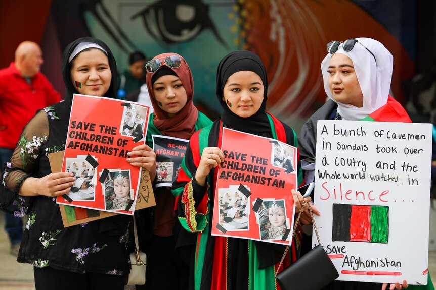A photo of four women holding posters that say 'Save the Children of Afghanistan'.