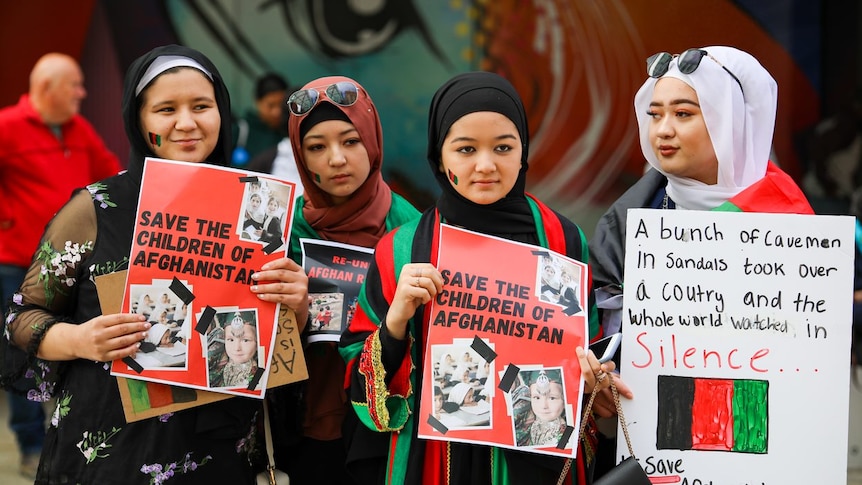 A photo of four women holding posters that say 'Save the Children of Afghanistan'.