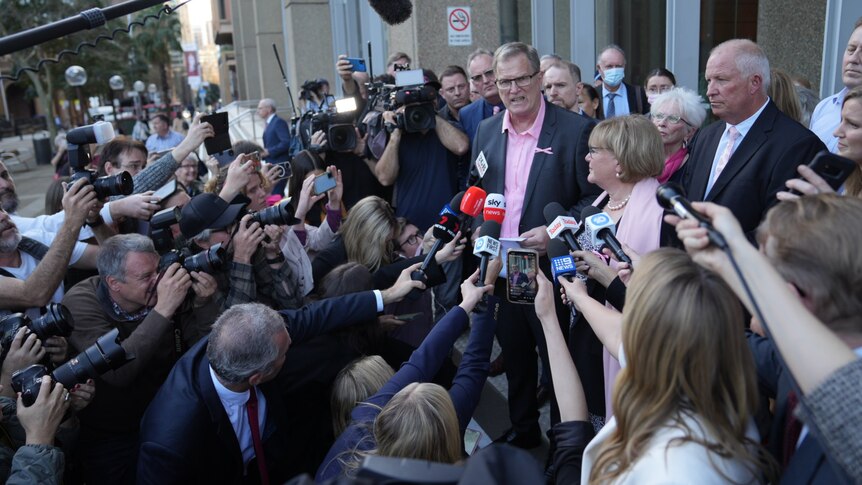 A man speaks to a large number of reporters