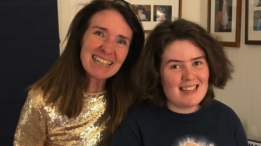 Mother and daughter standing in front of photos.