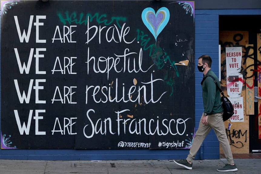 A man in a face mask walks past a sign during the coronavirus outbreak in San Francisco