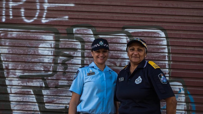 Two women in police uniform stand together.