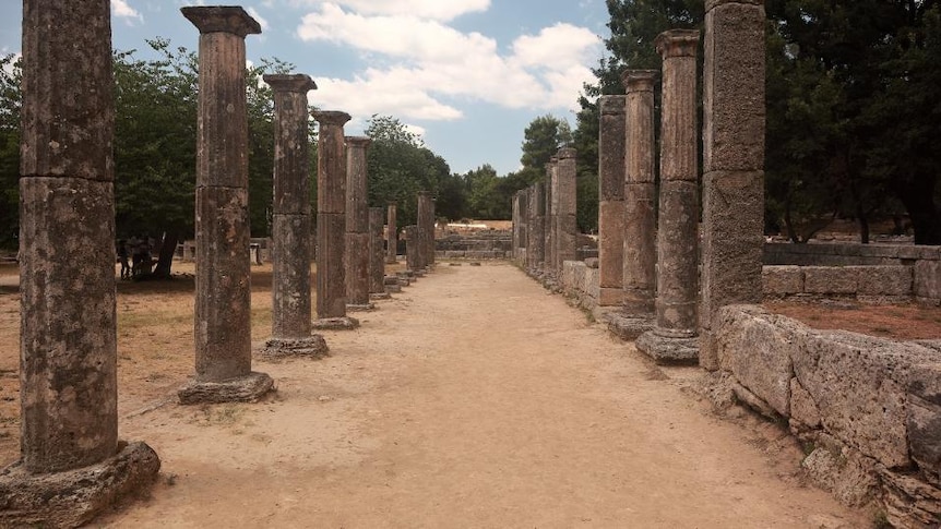 An outdoor archaeological site shows two rows of stone columns