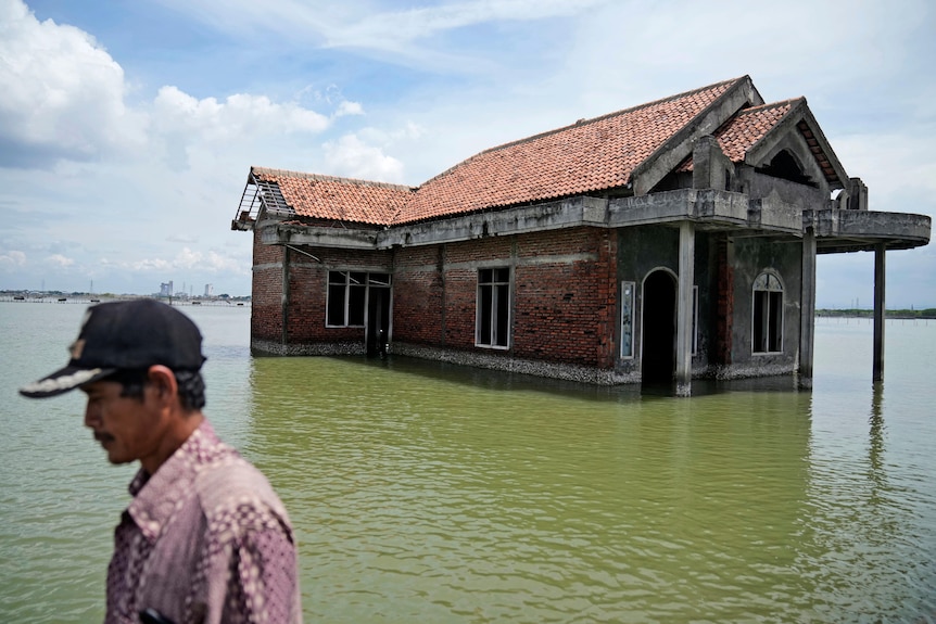 An abandoned house sits in water due to rising sea levels