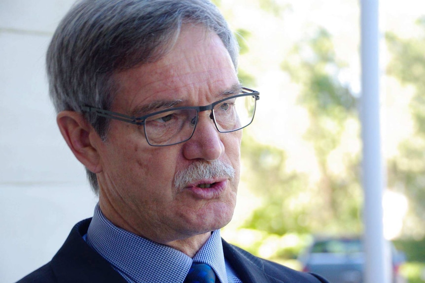 Head and shoulders profile shot of WA Treasuer Mike Nahan as he talks to reporters.