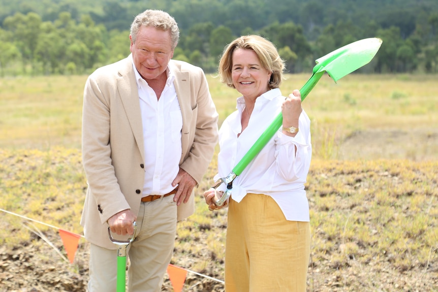 A man and a woman outside holding green shovels