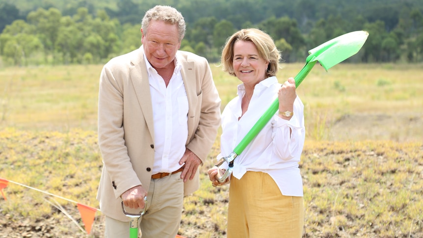 A man and a woman outside holding green shovels.