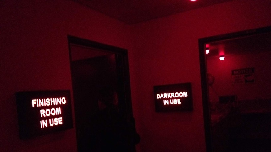 Red lit rooms display signs reading "finishing room in use" and "darkroom in use".