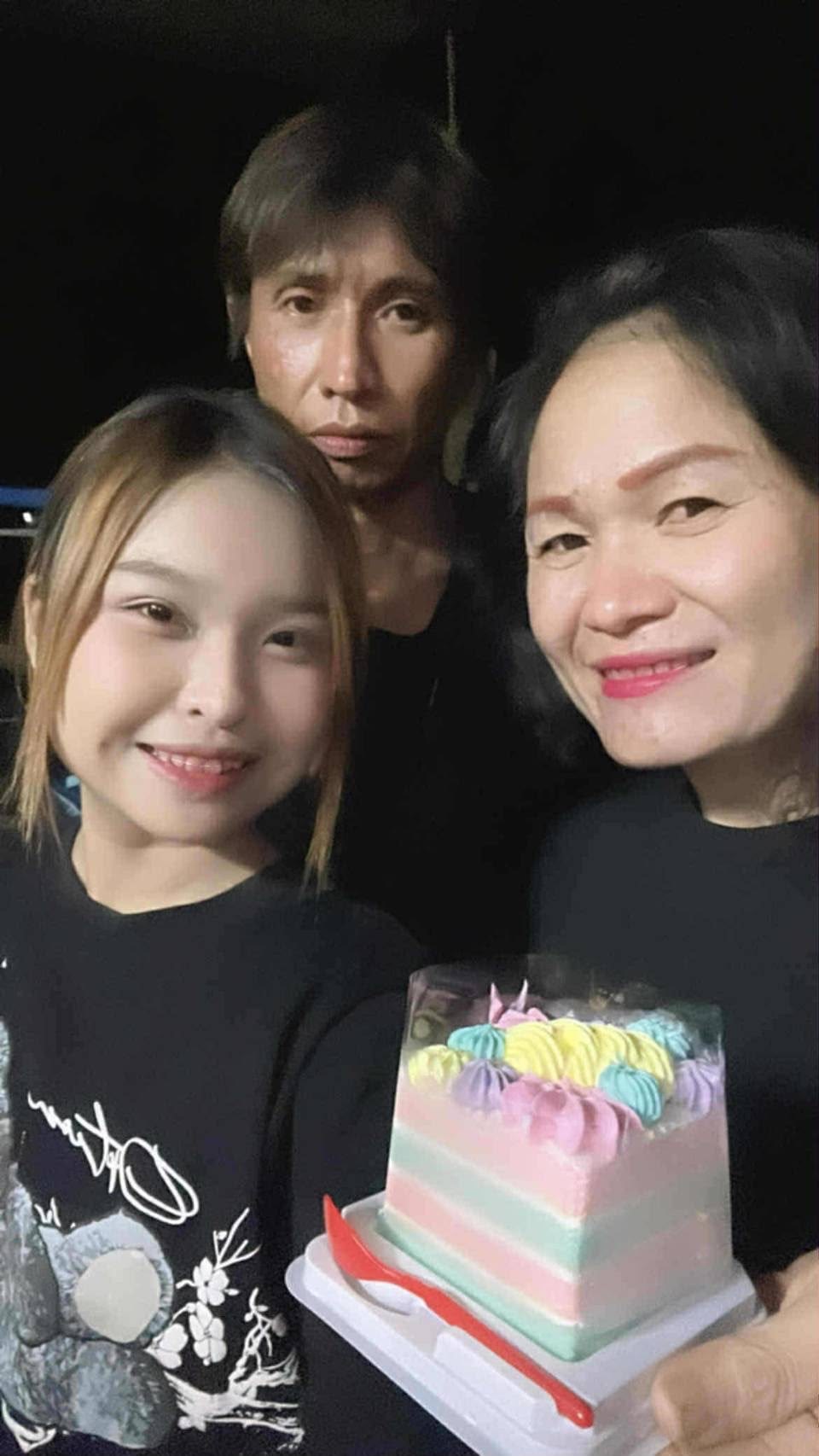 A teenage girl with a man and a woman holding a birthday cake 