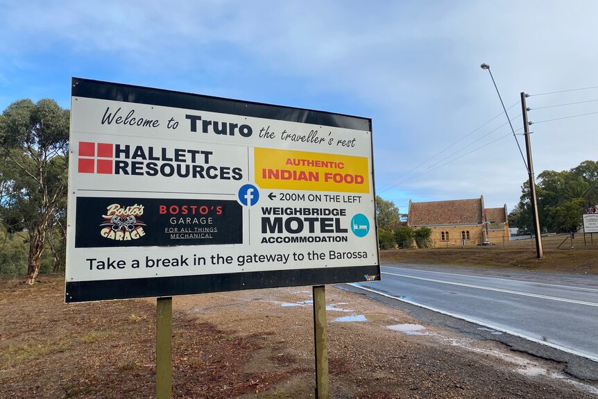 A sign with various business logos on it that says Welcome to Truro, the travellers rest at the top. 