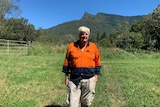 Farm owner John Qualye on his northern New South Wales property with the The Pinnacle landmark behind him.