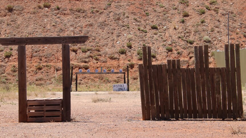 a wooden stockade in front of some distant pistol targets