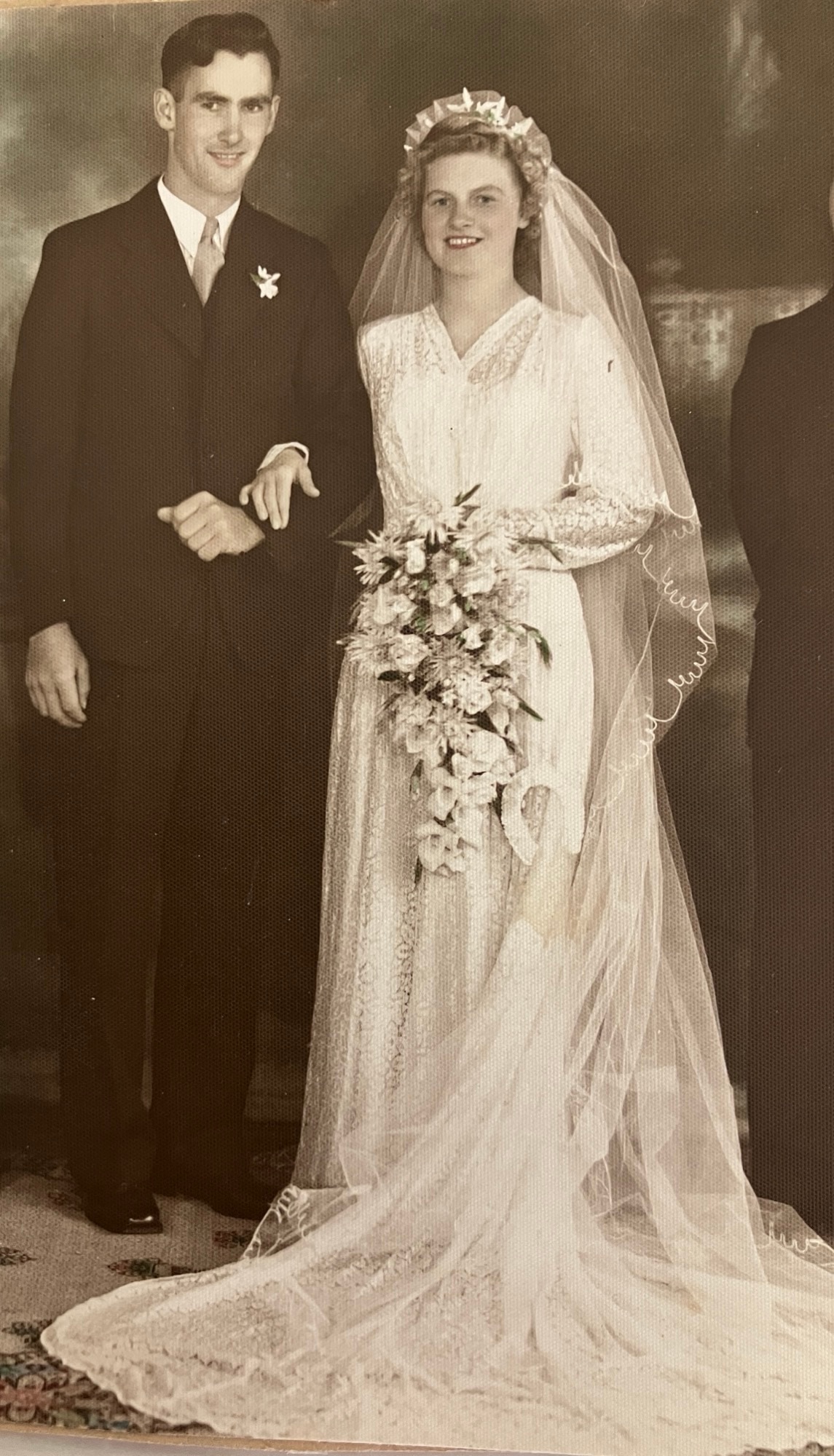 A sepia photo of a young couple wearing bridal clothing, smiling at the camera.