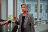 Penny Wong holds up her hand while speaking to the media