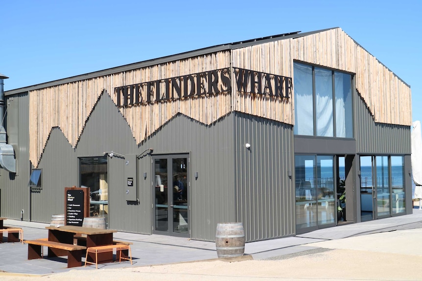 a large building converted into a cafe overlooks the beach