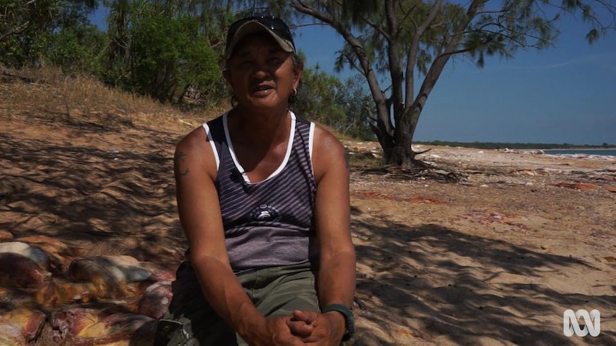 Indigenous man sits beside sea