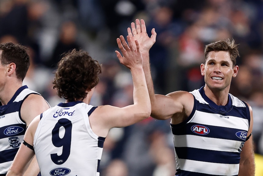 Tom Hawkins smiles and high-fives a teammate