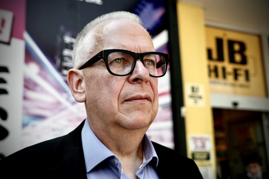 Man in glasses stands outside a JB Hi-Fi store in Sydney.